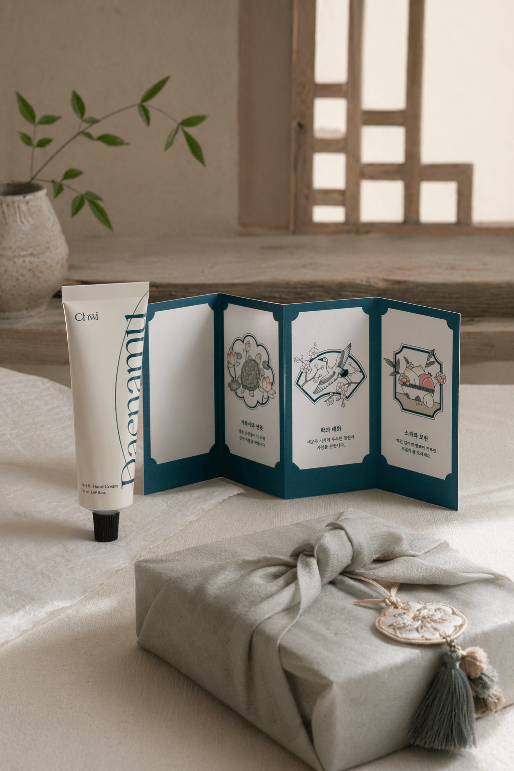Wrapped fragrance gifts beside hanji textures and softly lit scent objects.